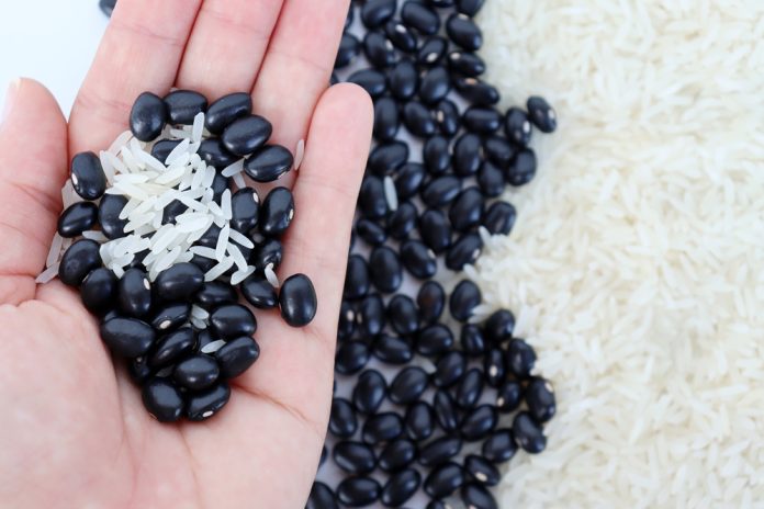 Girl's,Hand,Holding,Grains,Of,White,Rice,And,Black,Beans.