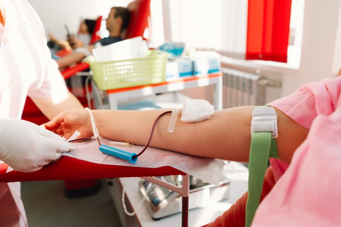 Young woman making blood donation in hospital.