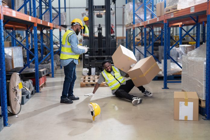 African american working in warehouse got accident from carry box, forklift truck working near by