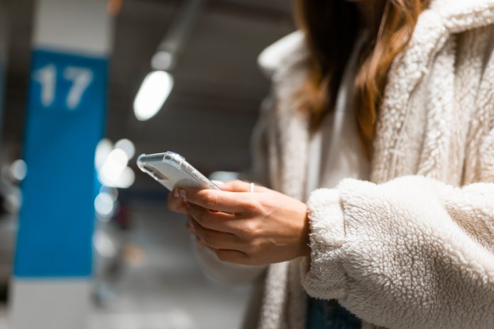 Woman hand with cell phone in hand in underground car parking