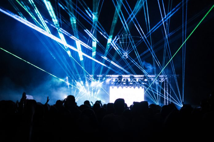 Colorful laser lights and audience at music concert.