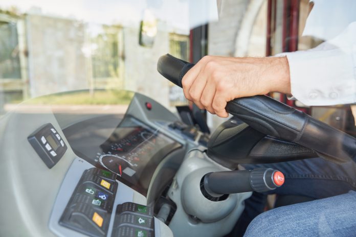 Professional male driver driving bus during work time.