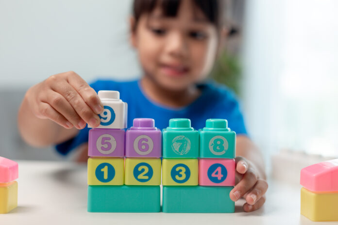 Little child girl playing colorful blocks